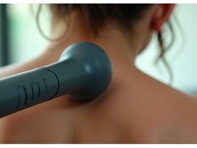 A Theragun Elite percussion device in action, providing deep tissue massage on a person's shoulder for muscle recovery and tension relief.
